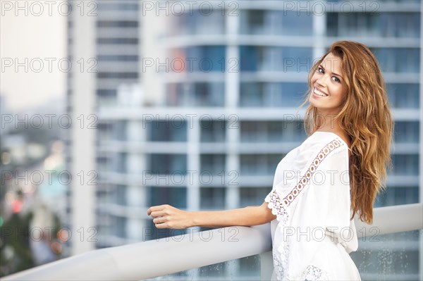 Hispanic woman standing on urban balcony