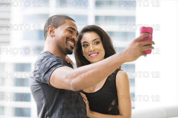 Couple taking selfie with cell phone on urban balcony