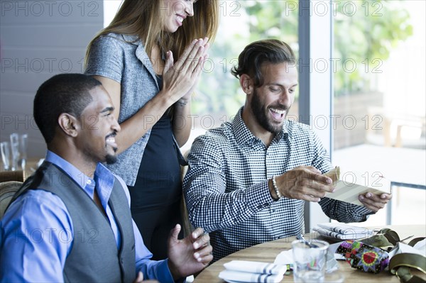 Businessman opening gifts at birthday lunch