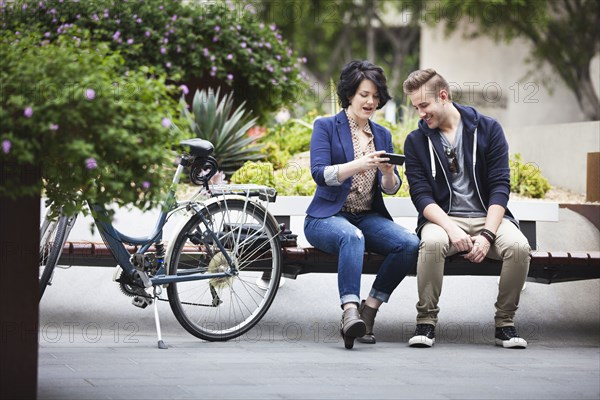 Caucasian business people using cell phone on bench