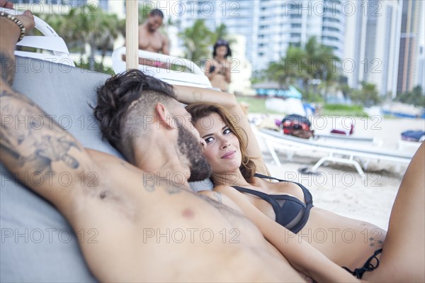 Couple laying on lawn chairs on beach