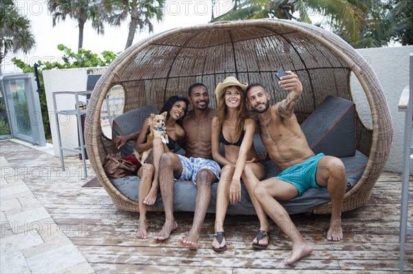 Friends taking selfie with cell phone in cabana