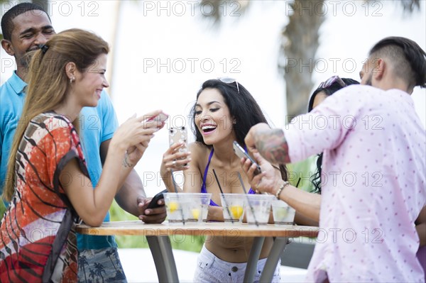 Friends using cell phone at table outdoors