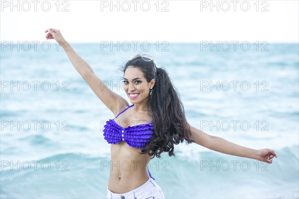 Hispanic woman playing in ocean
