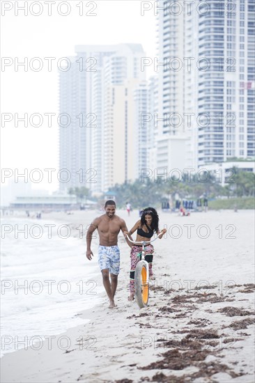 Couple riding bicycle on urban beach