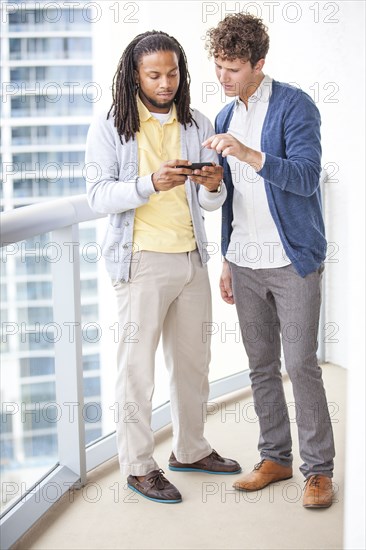 Businessmen using cell phone on urban balcony