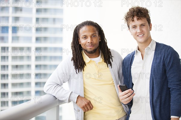 Businessmen using cell phone on urban balcony