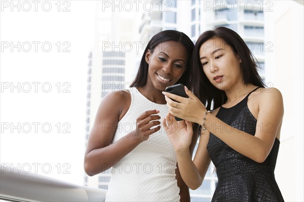 Women using cell phone on urban balcony