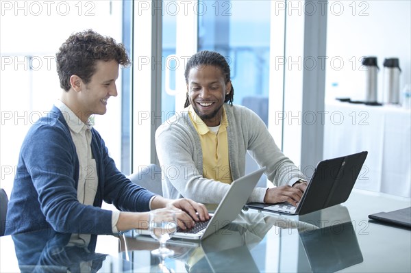 Businessmen working on laptops in office meeting