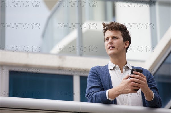 Caucasian businessman using cell phone on balcony