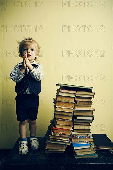 Boy standing near stacks of books