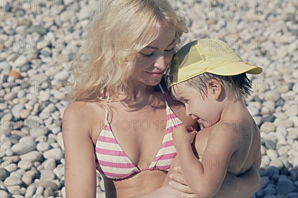 Mother holding son on rocky beach