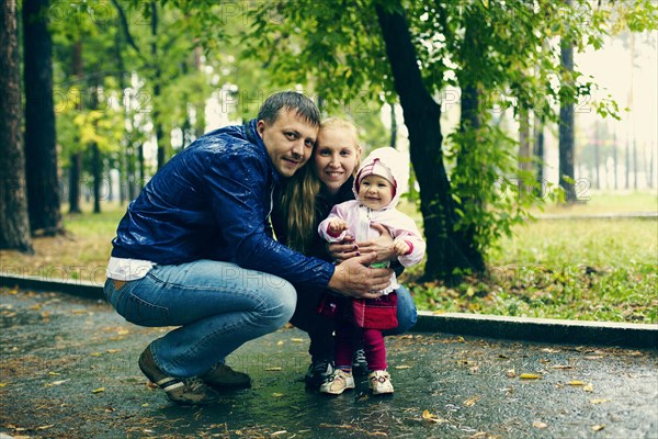 Caucasian family smiling on rainy path in park