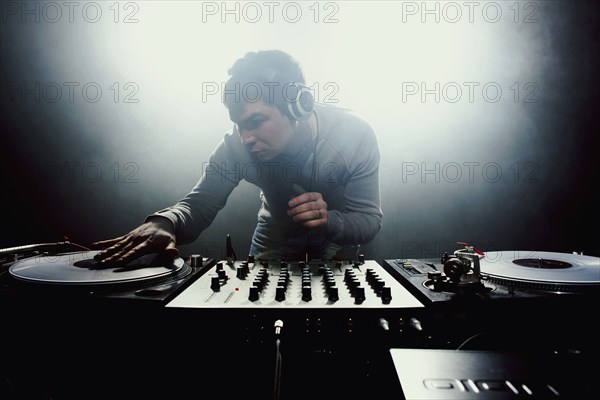 Caucasian disc jockey playing music in nightclub