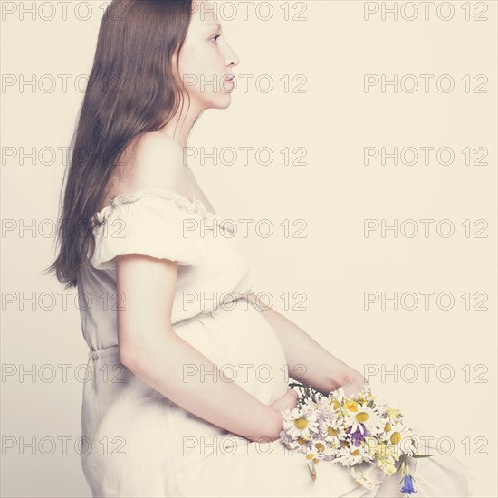 Pregnant Caucasian woman holding bouquet of flowers