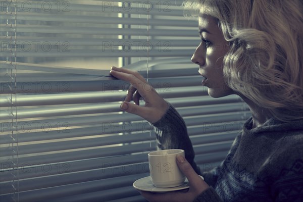 Caucasian woman peering through blinds