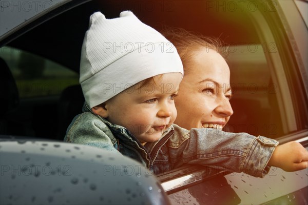 Caucasian mother and son looking out car window