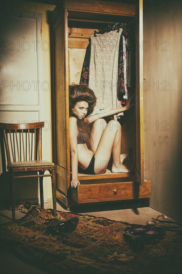Caucasian woman sitting in wardrobe wearing underwear