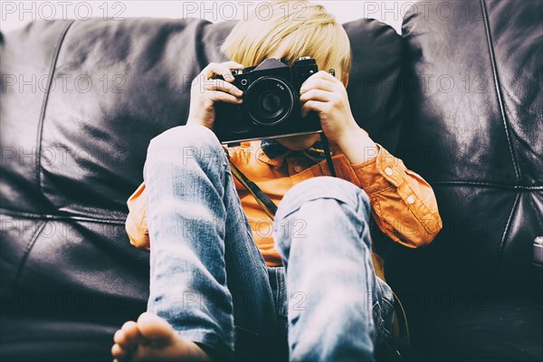 Caucasian boy sitting on sofa using camera