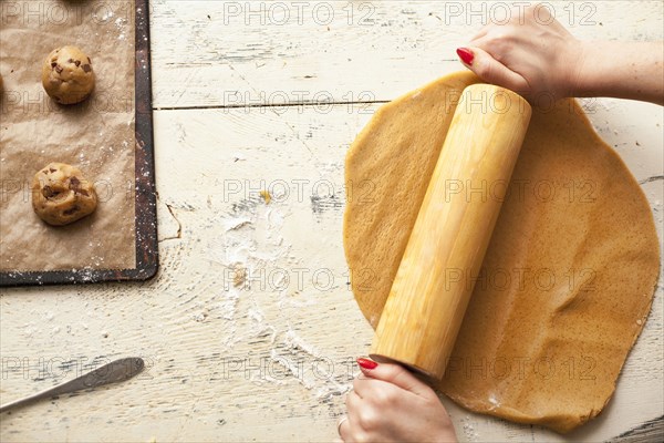 Hands of woman using rolling pin on cookie dough