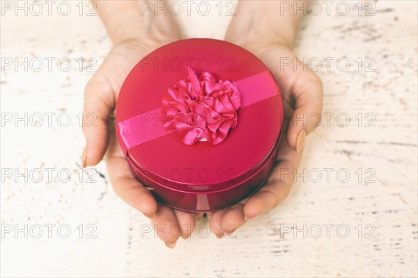 Hands of woman holding round gift box