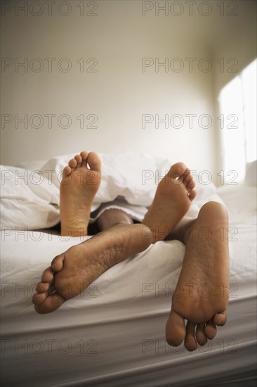 Barefeet of couple laying in bed together