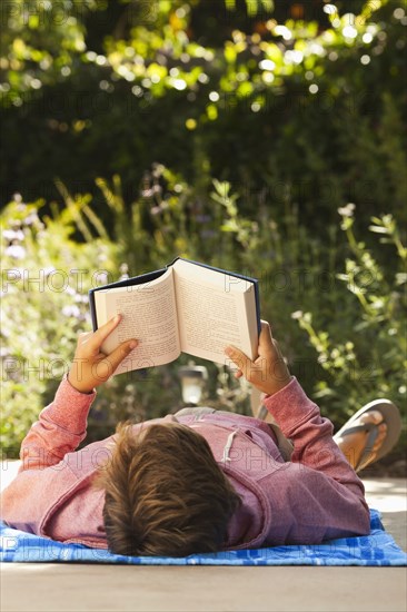 Caucasian teenager reading outdoors