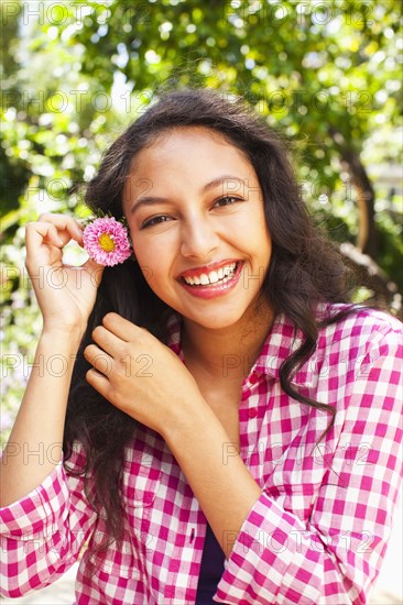 Mixed race teenager putting flower in hair