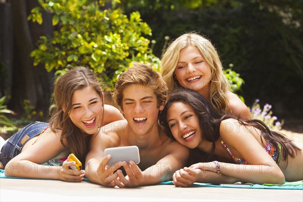 Friends laying outdoors together looking at cell phone