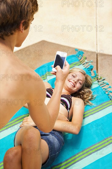 Caucasian teenager taking cell phone picture of girlfriend