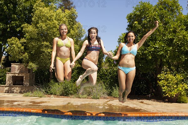 Girls jumping into swimming pool together