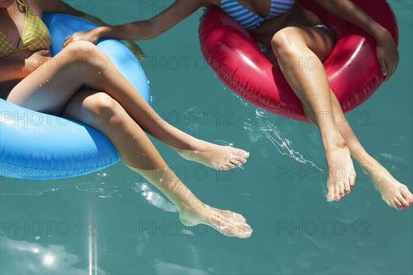 Girls sitting in inflatable rings in swimming pool