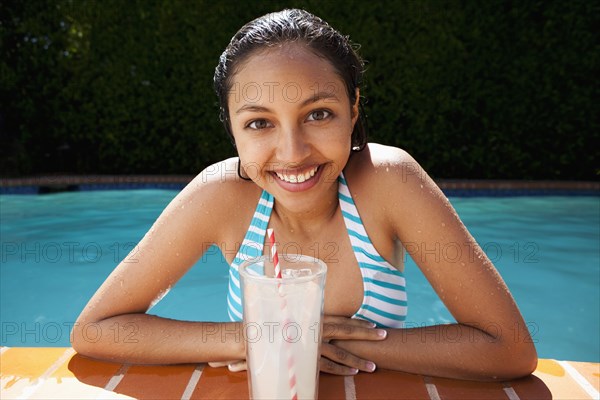 Mixed race girl drinking lemonade near swimming pool