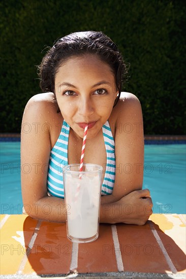 Mixed race girl drinking lemonade near swimming pool