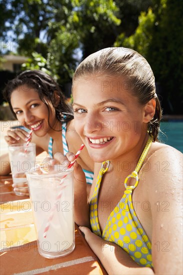 Girls drinking lemonade near swimming pool