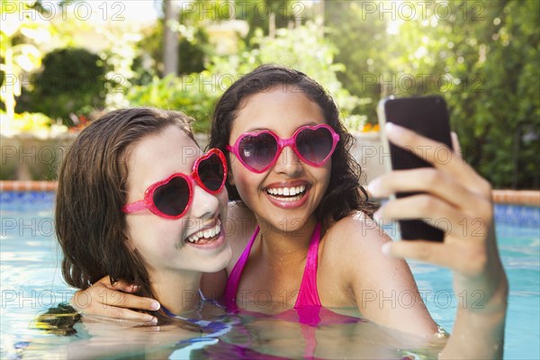 Friends in swimming pool looking at cell phone