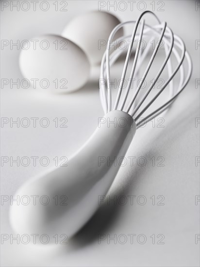 Close up of white whisk and eggs