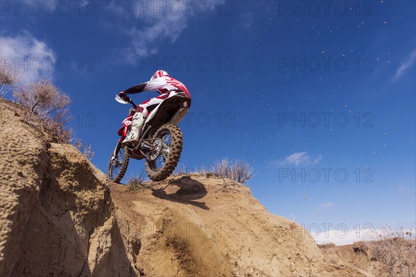 Motorcyclist riding dirt bike on hillside