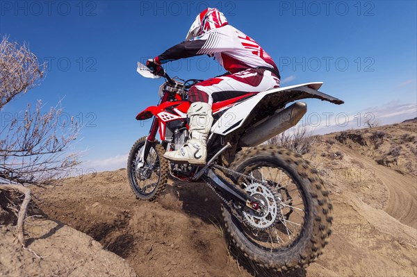 Motorcyclist riding dirt bike on hillside