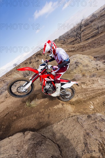 Motorcyclist riding dirt bike on hillside