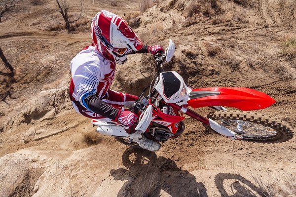 Motorcyclist riding dirt bike on hillside