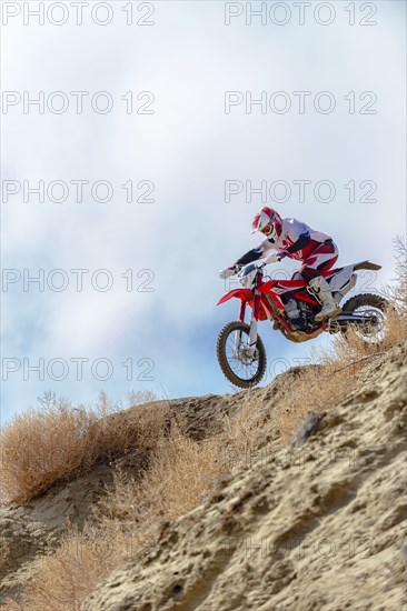 Motorcyclist riding dirt bike on hillside