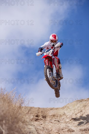 Motorcyclist riding dirt bike on hillside