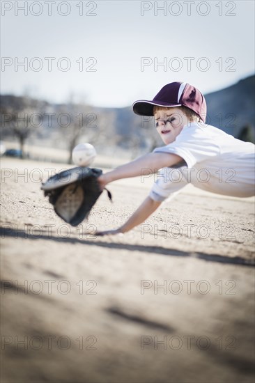 Caucasian boy catching baseball on field