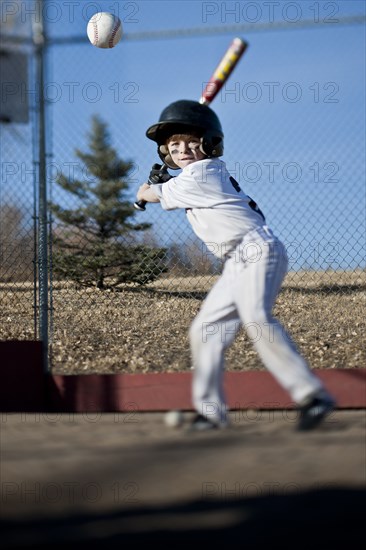 Caucasian boy hitting baseball on field