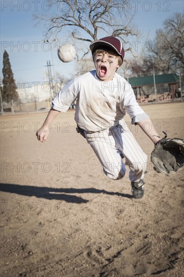 Caucasian boy catching baseball on field