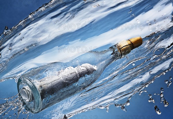 Close up of message in a bottle splashing in water