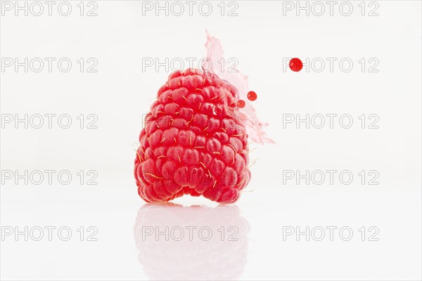 Close up of juice splashing on raspberry