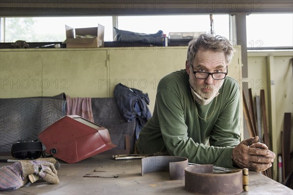 Artist leaning on table in workshop