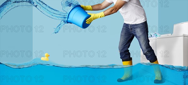 Man throwing water from bucket in flooding laundry room